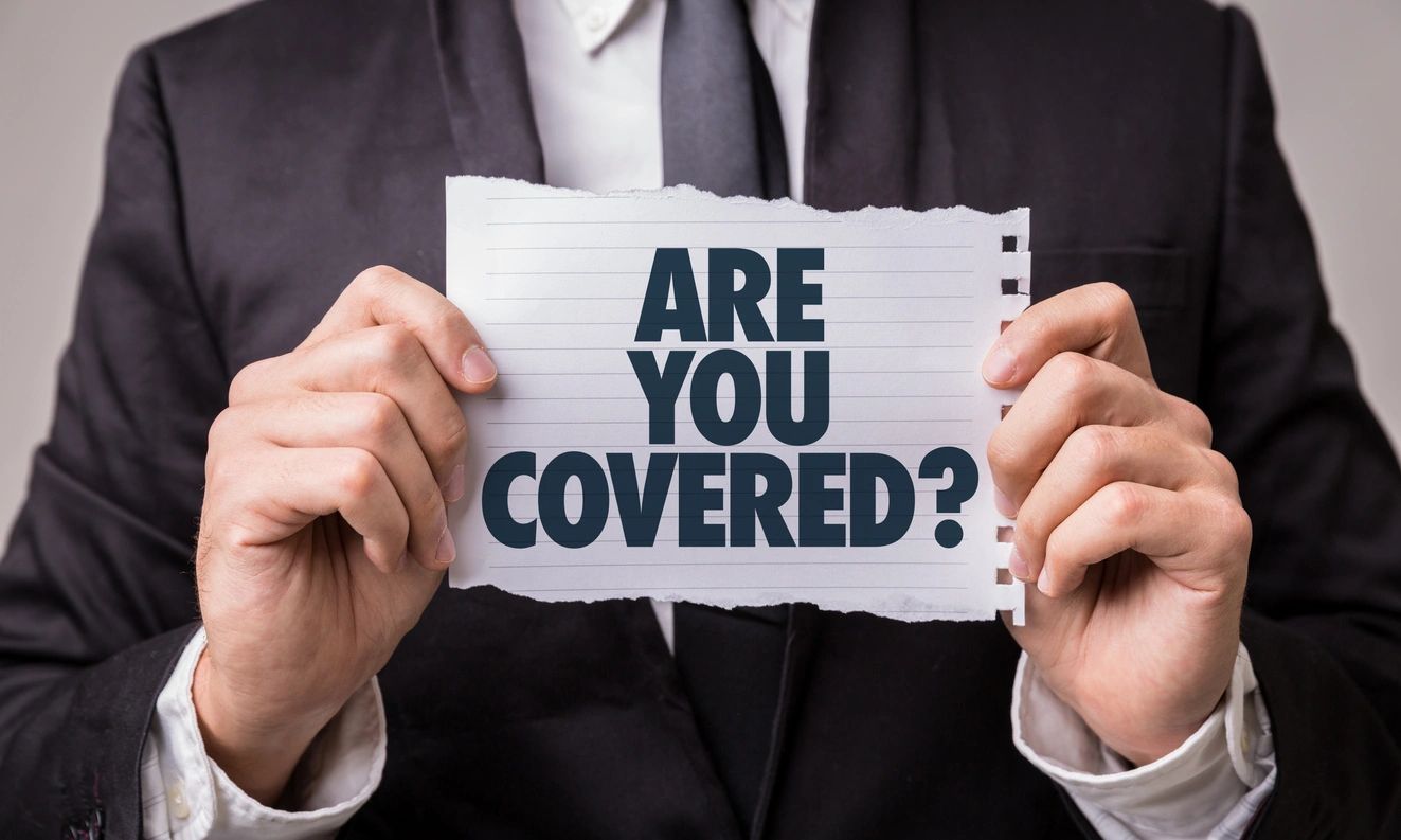 sign that says "Are you covered?" held by man in suit